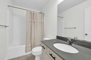 Full bathroom with vanity, shower / tub combo, tile patterned flooring, and toilet