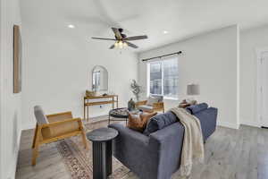 Living room with ceiling fan and light hardwood / wood-style floors