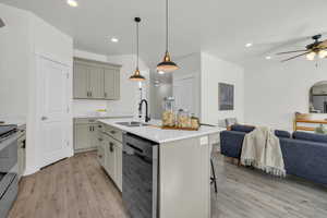 Kitchen with decorative light fixtures, an island with sink, sink, a kitchen breakfast bar, and stainless steel range with electric stovetop