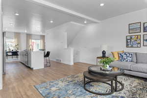 Living room featuring beam ceiling, a textured ceiling, and light wood-type flooring