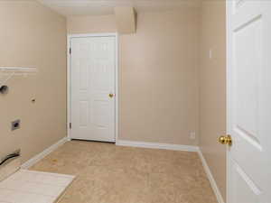 Washroom with light tile patterned floors and hookup for an electric dryer