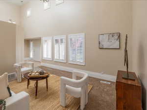 Living area featuring light carpet and a high ceiling