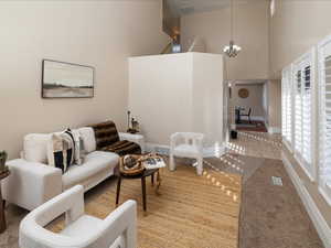 Living room featuring carpet flooring, a chandelier, and a high ceiling