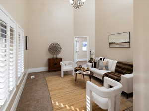 Carpeted living room featuring a towering ceiling and a notable chandelier