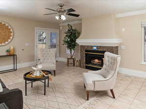 Living room featuring light tile patterned floors, crown molding, a high end fireplace, and ceiling fan