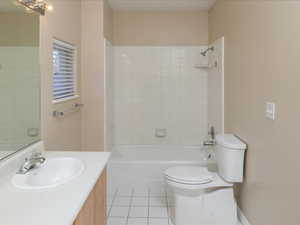 Full bathroom with vanity, tiled shower / bath, tile patterned flooring, and toilet