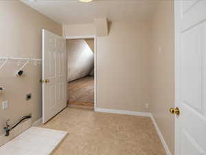 Clothes washing area featuring hookup for an electric dryer and light tile patterned floors