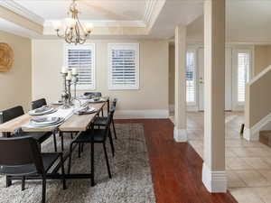 Dining space with a raised ceiling, crown molding, hardwood / wood-style flooring, and an inviting chandelier