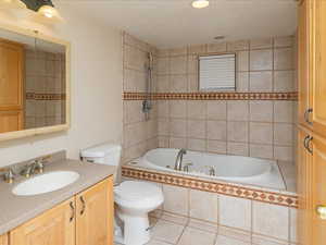 Full bathroom featuring vanity, tile patterned flooring, tiled shower / bath combo, and toilet