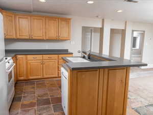 Kitchen featuring sink, white appliances, and an island with sink