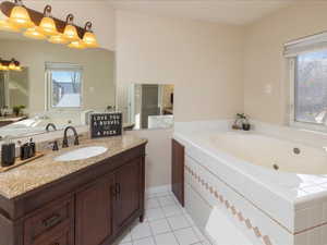 Bathroom featuring vanity, tile patterned floors, and tiled bath