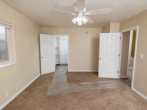 Carpeted empty room with ceiling fan and a textured ceiling