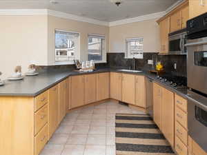 Kitchen featuring light brown cabinetry, sink, light tile patterned floors, and appliances with stainless steel finishes