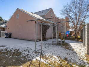 Snow covered back of property with a playground