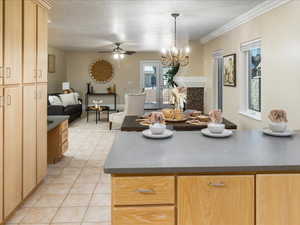 Kitchen featuring light brown cabinetry, a textured ceiling, light tile patterned floors, pendant lighting, and ceiling fan with notable chandelier