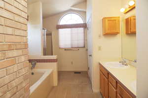 Bathroom with lofted ceiling, vanity, and plus walk in shower