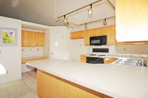 Kitchen featuring rail lighting, light brown cabinetry, sink, and white range with electric stovetop