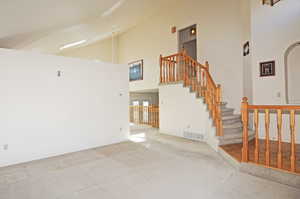 Interior space featuring a high ceiling and light colored carpet