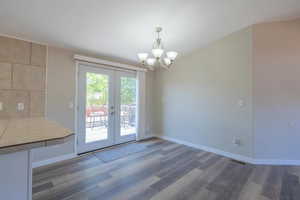 Unfurnished dining area with a chandelier, dark hardwood / wood-style flooring, and french doors