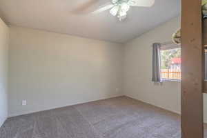 Carpeted spare room with lofted ceiling and ceiling fan