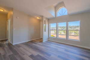 Empty room featuring hardwood / wood-style flooring and vaulted ceiling