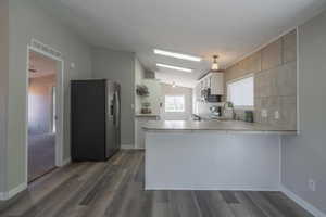 Kitchen featuring appliances with stainless steel finishes, lofted ceiling, sink, dark hardwood / wood-style flooring, and kitchen peninsula