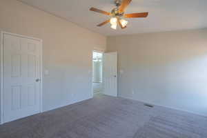 Spare room featuring carpet, ceiling fan with notable chandelier, and lofted ceiling