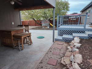 View of patio featuring a playground, a deck, and ceiling fan