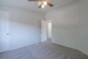 Empty room featuring vaulted ceiling, light colored carpet, and ceiling fan