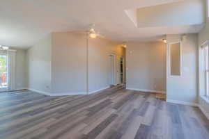 Unfurnished room with lofted ceiling, ceiling fan with notable chandelier, and dark hardwood / wood-style flooring