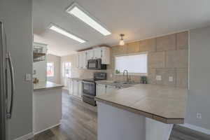 Kitchen featuring white cabinetry, sink, stainless steel appliances, and kitchen peninsula