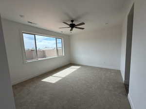 Unfurnished room with baseboards, visible vents, dark carpet, and ceiling fan