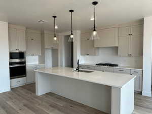 Kitchen with a sink, stainless steel appliances, light wood-style flooring, and light countertops