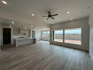 Unfurnished living room featuring baseboards, recessed lighting, a ceiling fan, and light wood-style floors