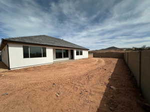 Rear view of house with stucco siding, a tile roof, and a fenced backyard