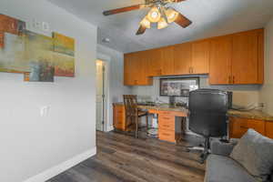 Office space with ceiling fan, dark wood-type flooring, and a textured ceiling