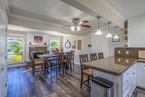 Kitchen with white cabinetry, a fireplace, kitchen peninsula, and dark wood-type flooring