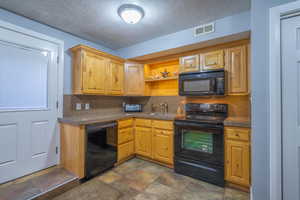 Kitchen with tasteful backsplash, sink, a textured ceiling, and black appliances