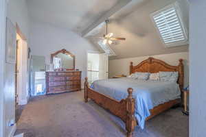 Carpeted bedroom featuring vaulted ceiling with beams and ceiling fan