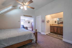 Carpeted bedroom with connected bathroom, sink, a wall mounted air conditioner, high vaulted ceiling, and ceiling fan