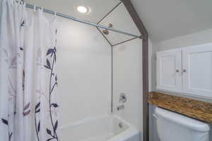 Bathroom with shower / bath combination with curtain and toilet