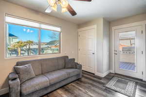 Living room with ceiling fan, dark wood-type flooring, and a healthy amount of sunlight