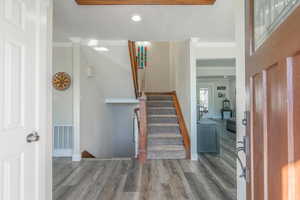 Staircase with crown molding, wood-type flooring, and a textured ceiling