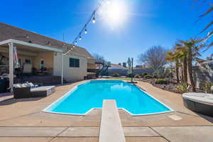 View of pool with a diving board, an outdoor hangout area, and a patio area