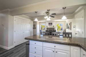 Kitchen with crown molding, hanging light fixtures, and white cabinets