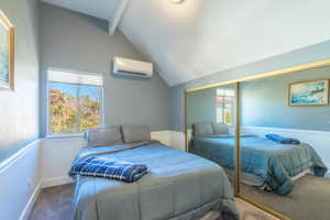 Bedroom with a wall mounted air conditioner, vaulted ceiling with beams, a closet, and carpet