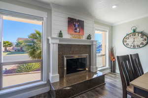 Living room featuring dark hardwood / wood-style flooring, a fireplace, ornamental molding, and a textured ceiling