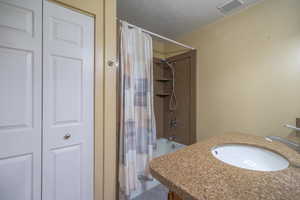 Bathroom featuring sink, shower / tub combo, and a textured ceiling