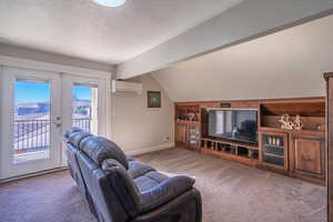 Living room with vaulted ceiling, carpet flooring, a wall unit AC, a textured ceiling, and french doors