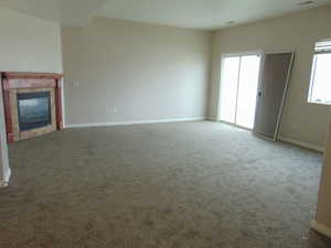 Unfurnished living room with a wealth of natural light, carpet floors, and a tile fireplace